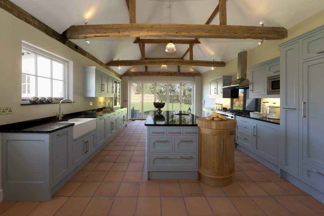 a beautiful farmhouse kitchen in a fully restored and rebuilt farm. Old, weathered oak beams support the roof and ceiling. Brand new terracotta flooring compliments the pastel toned powder blue cupboards and large kitchen island. This is a modern featured kitchen with all the appliances but constructed in a traditional style and being faithful to the 500 year old building.